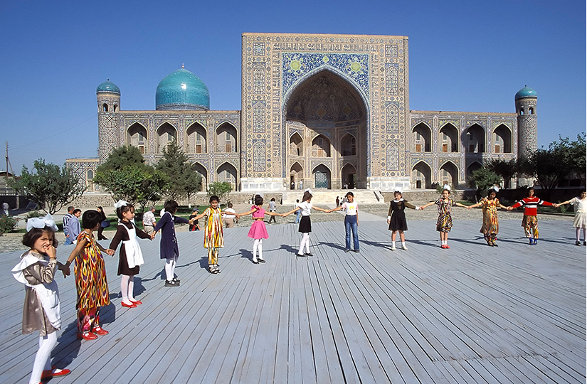 Girls dancing in front of the Tillya-Kori Medresseh, Registan, Samarkand, Uzbekistan