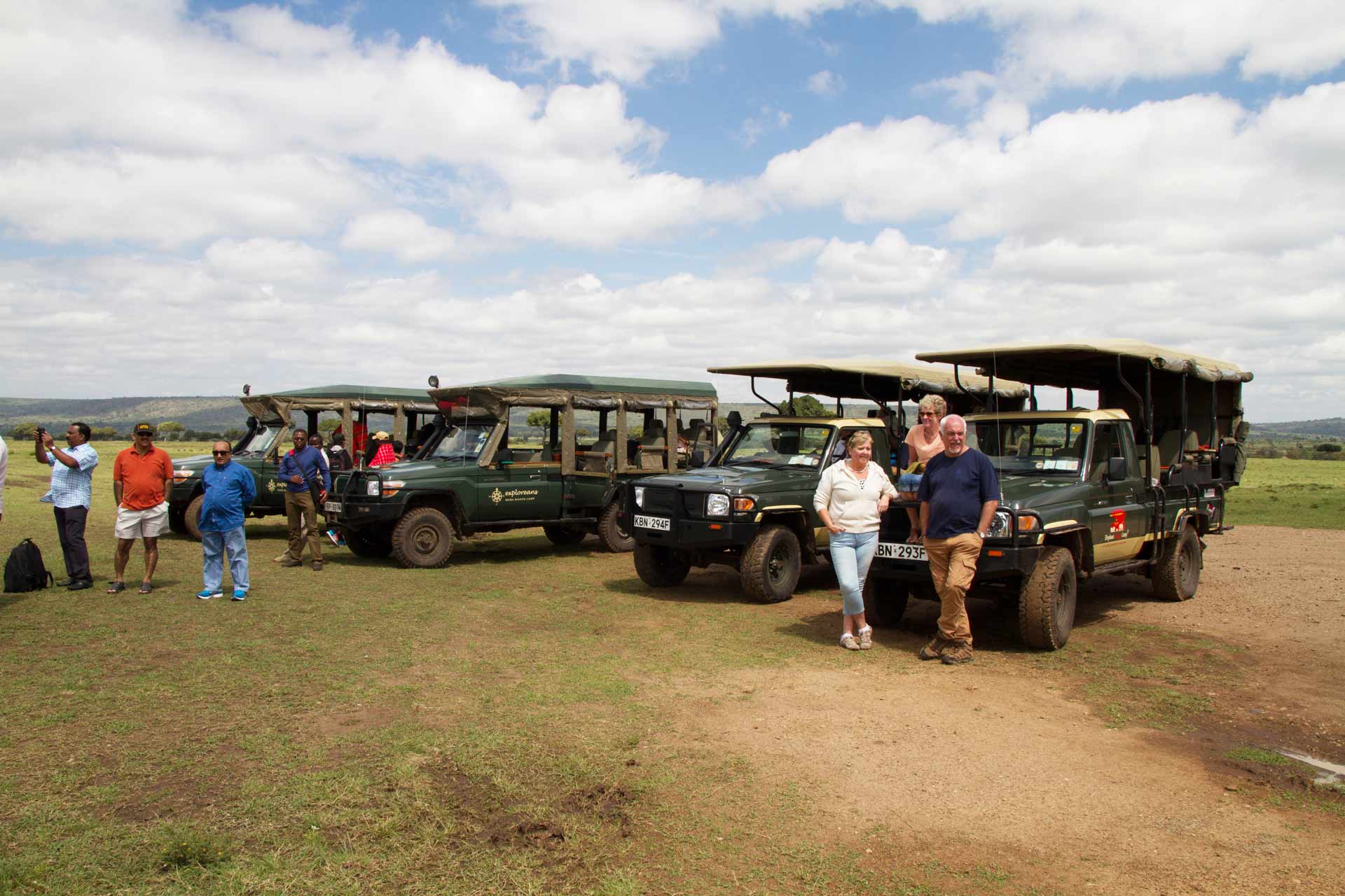 People waiting by safari vehicles at the airstrip, Masai Mara National Reserve, Kenya