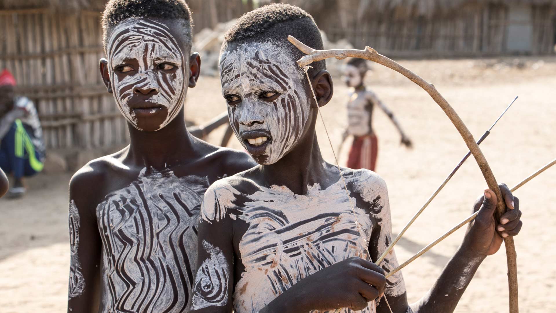 Karo boy wearing traditional face paint with bow and arrow at Kortcho Village, Omo Valley, Ethiopia