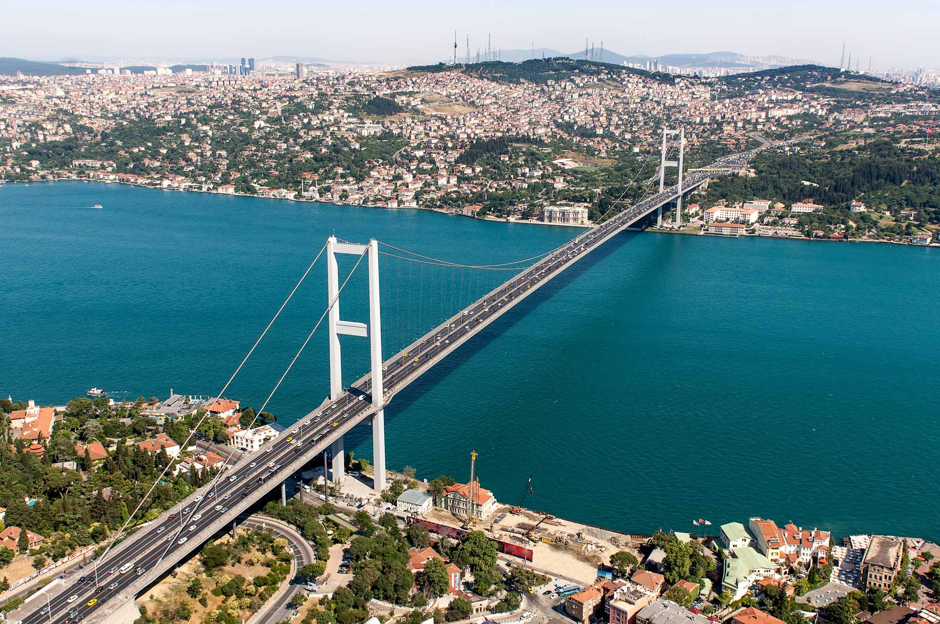 Bosphorus Bridge with background of Bosphorus strait on a sunny day with background cloudy blue sky and blue sea in Istanbul, Türkiye (Turkey).