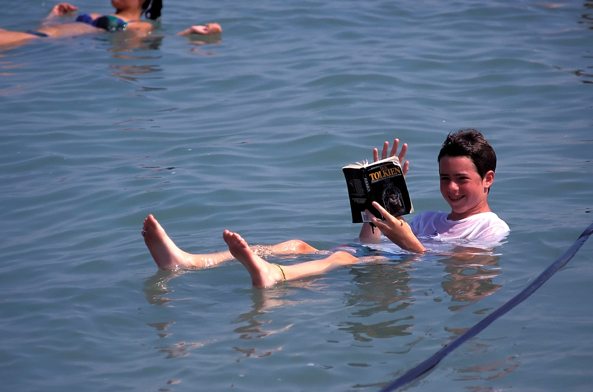 Boy floating and reading a book in the Dead Sea, Engedi, Israel
