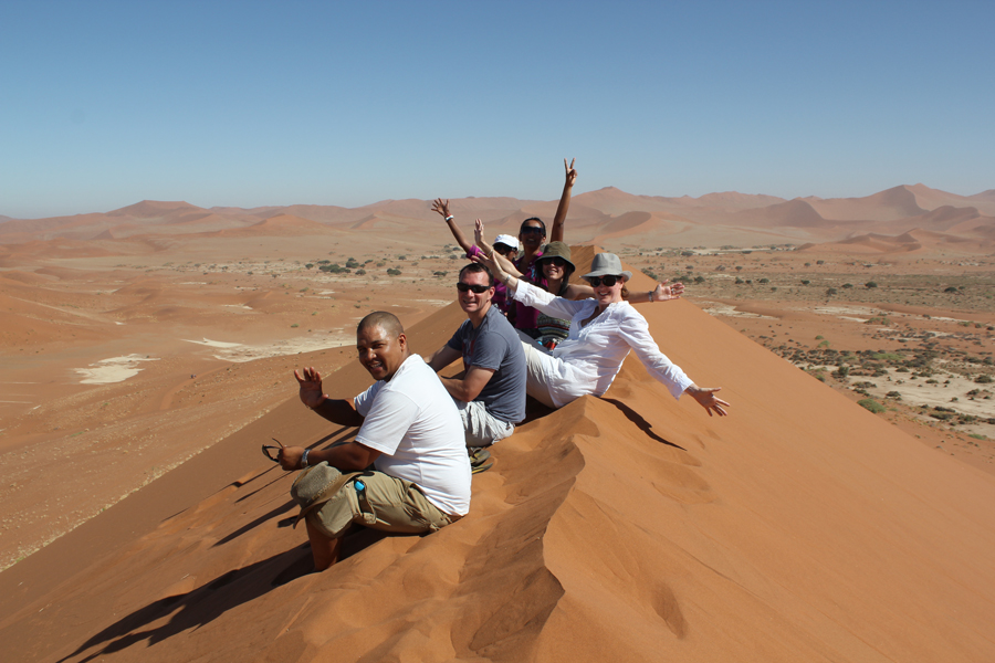 Tourists enjoying a red dune in Sossuslvei, Namib Naukluft National Park, Namib desert