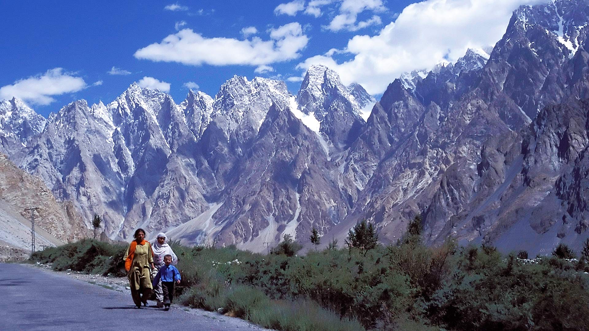 Women walking on the Karakoram Highway with the Little Karakoram Range in the background, Northern Areas, Pakistan