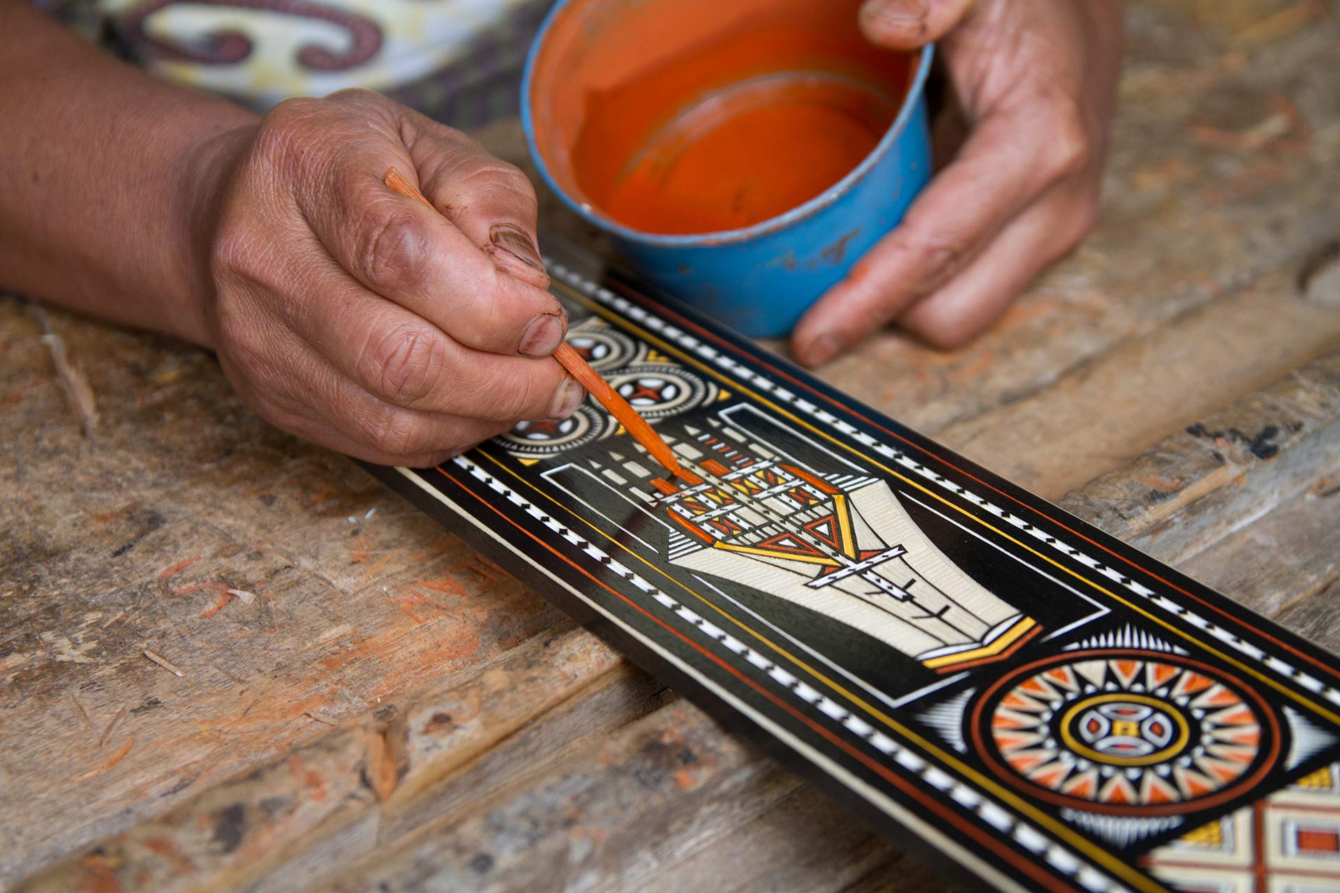 Man painting a traditional Toraja design on piece of wood, Kete Kesu, Toraja Land, South Sulawesi, Indonesia