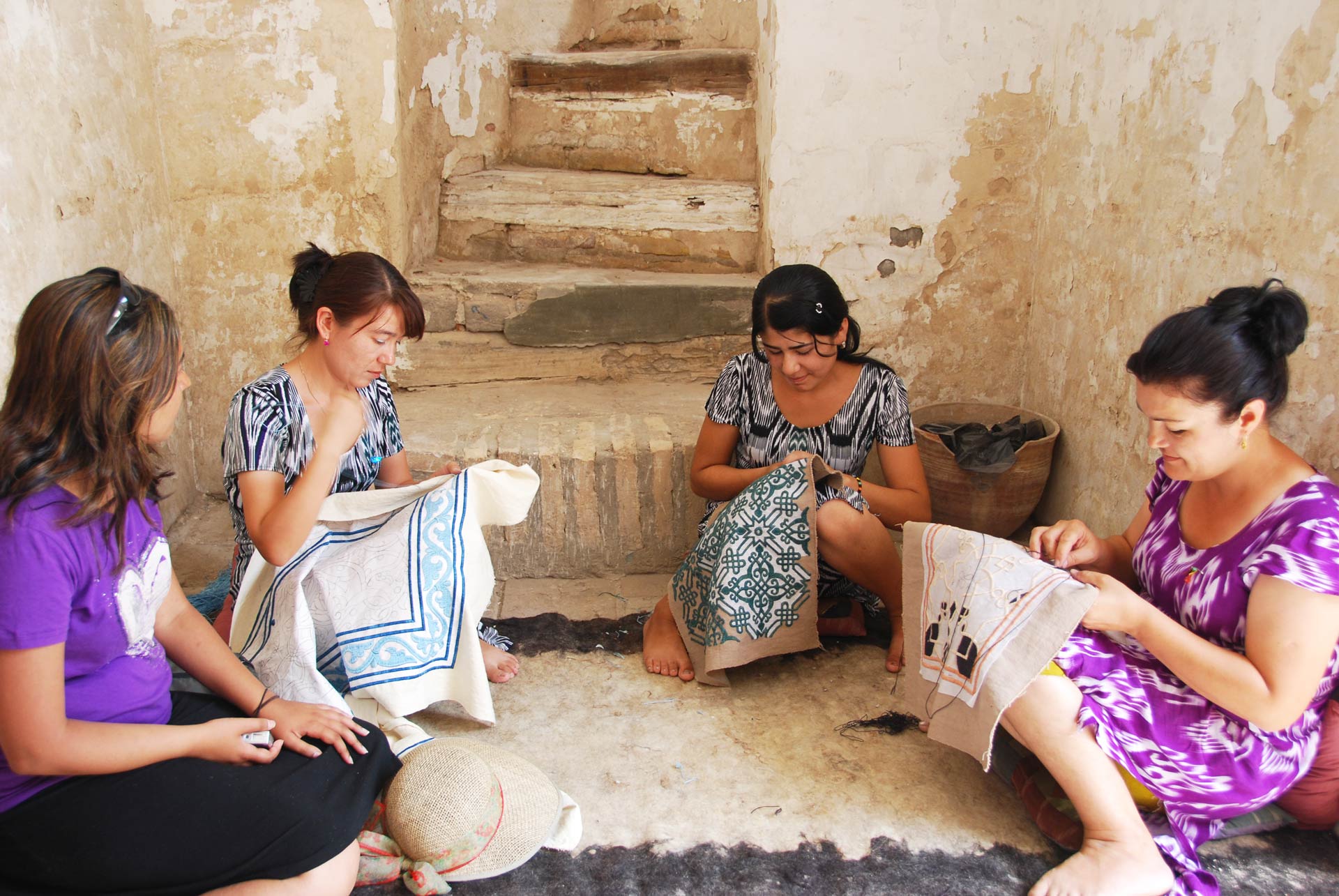 Uzbek women knotting handmade carpet in a workshop