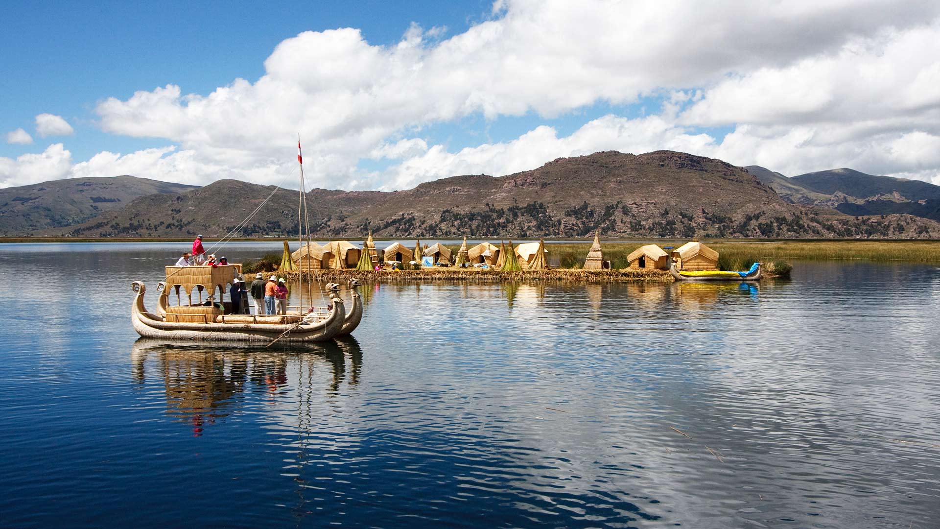 Totora (hollow reed) boat by a floating man-made totora island inhabitated by the Uro people in Lake Titicaca, near Puno