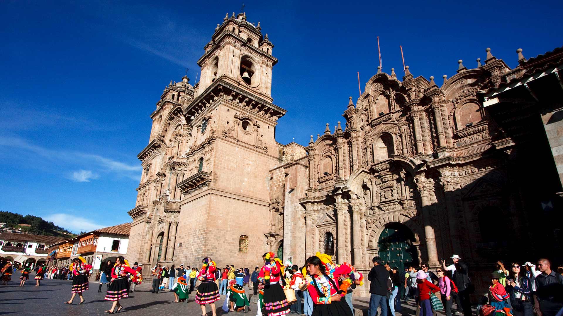 People wearing traditional dress performing a folk dance during a street festival in Cusco